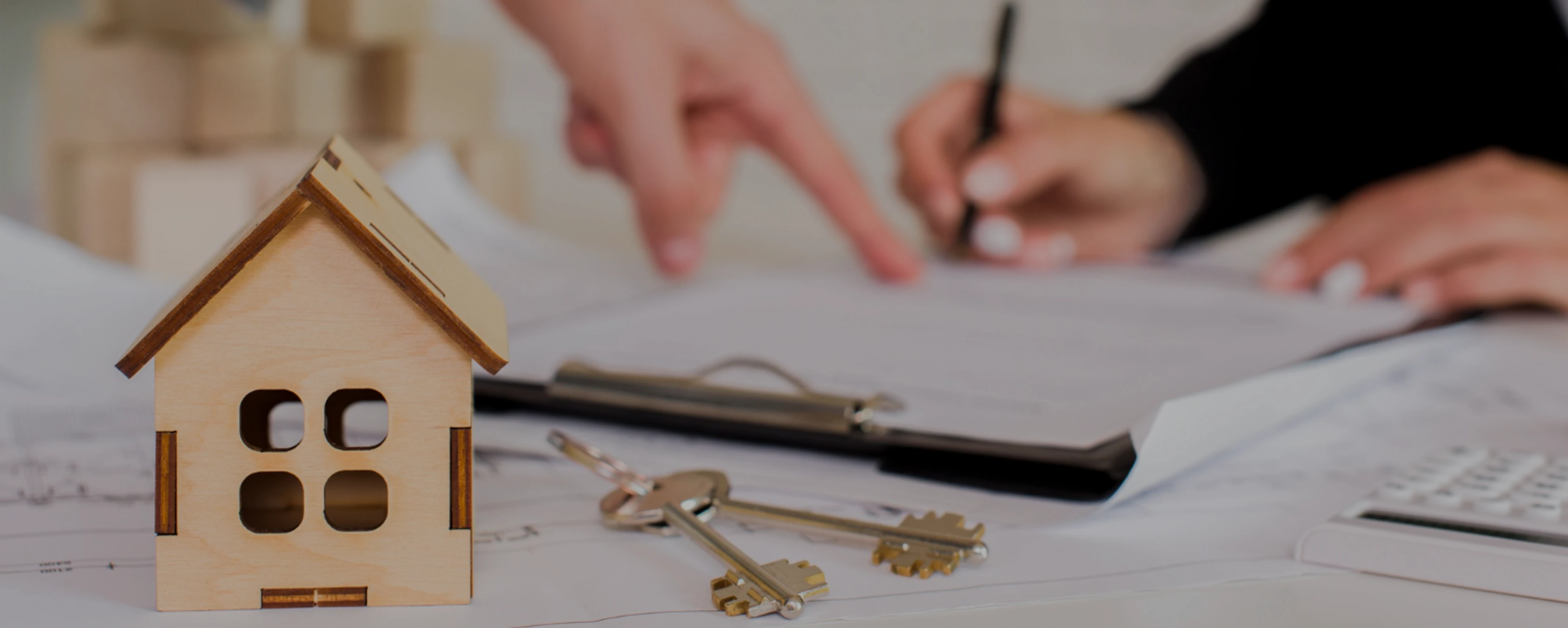 Wooden house model with keys on real estate documents